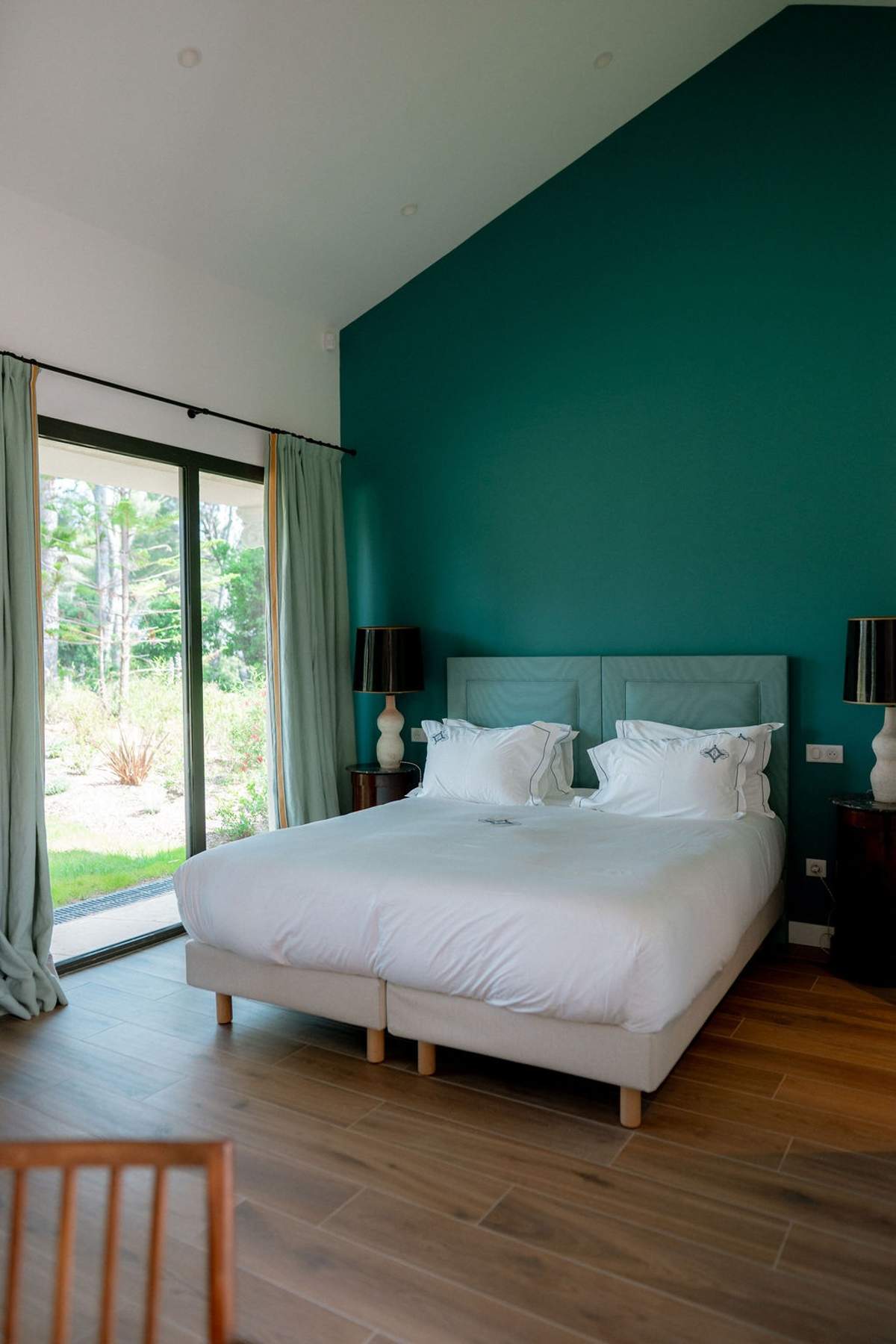 Teal-walled guest bedroom with garden view at Domaine Rocabella, French Riviera