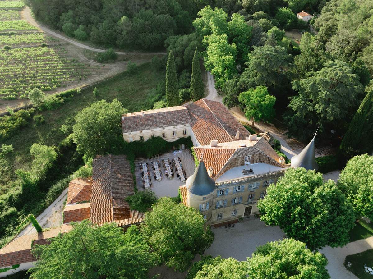 Aerial view of outdoor chateau courtyard wedding reception with long banquet tables and 80-100 guests
