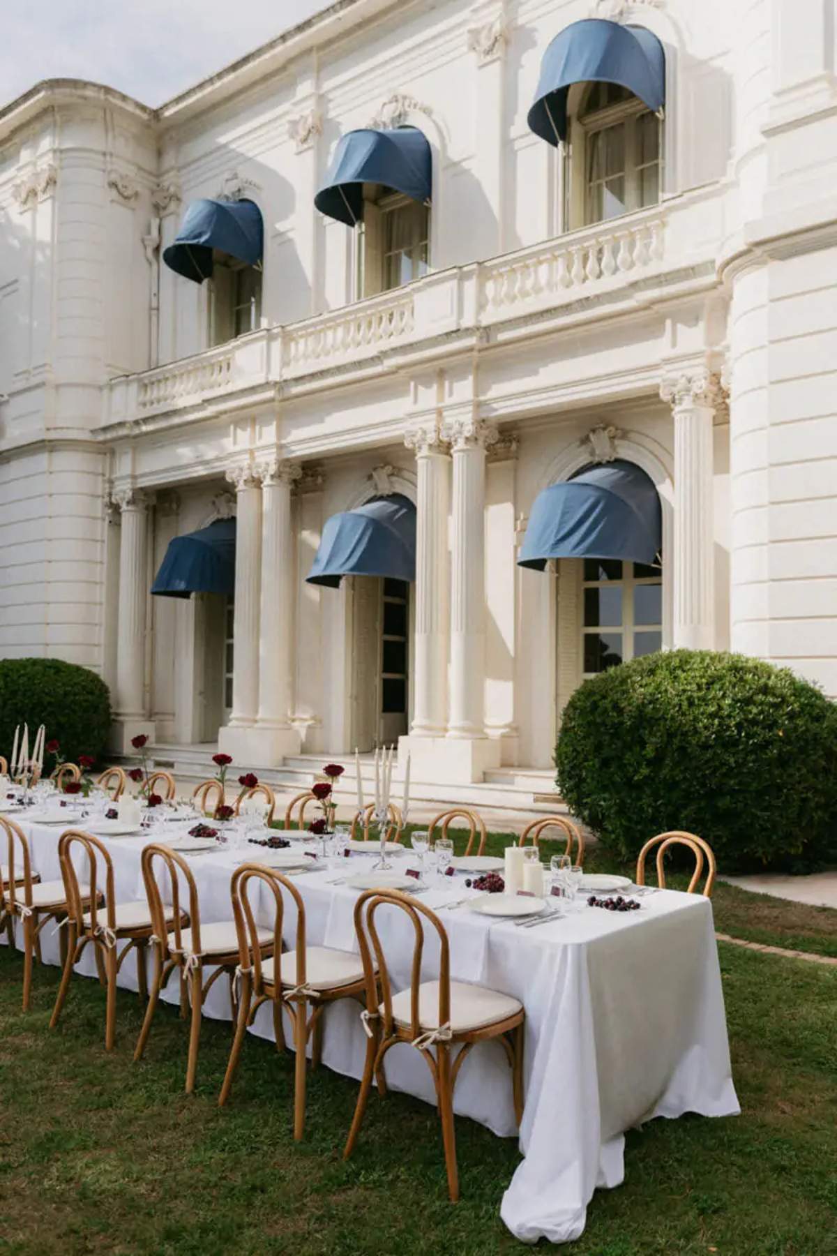 Dinner table set on the lawn in front of the villa facade at Domaine Rocabella, French Riviera