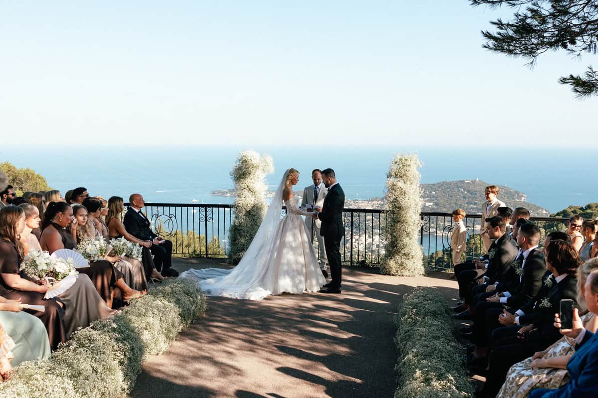 Clifftop wedding ceremony above the sea with baby's breath lining the aisle, planned by Be My Love Weddings