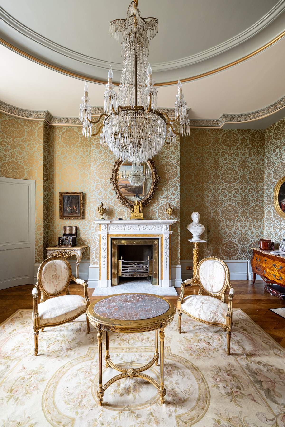 A salon at Château Changeux with a crystal chandelier and gilded furniture