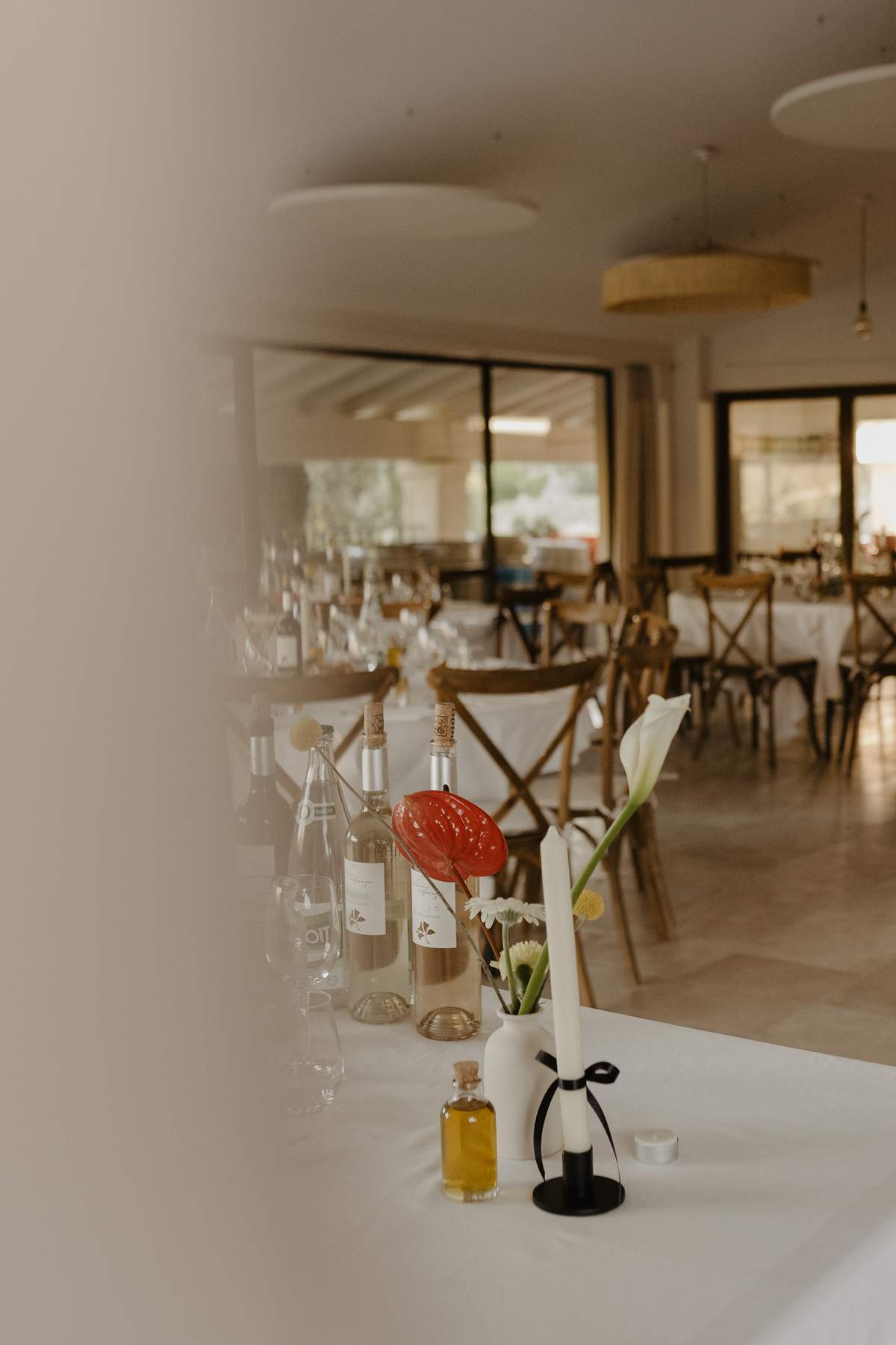 Estate wine and olive oil on a dinner table, with the reception room at Domaine ODDO Vallon des Glauges laid behind