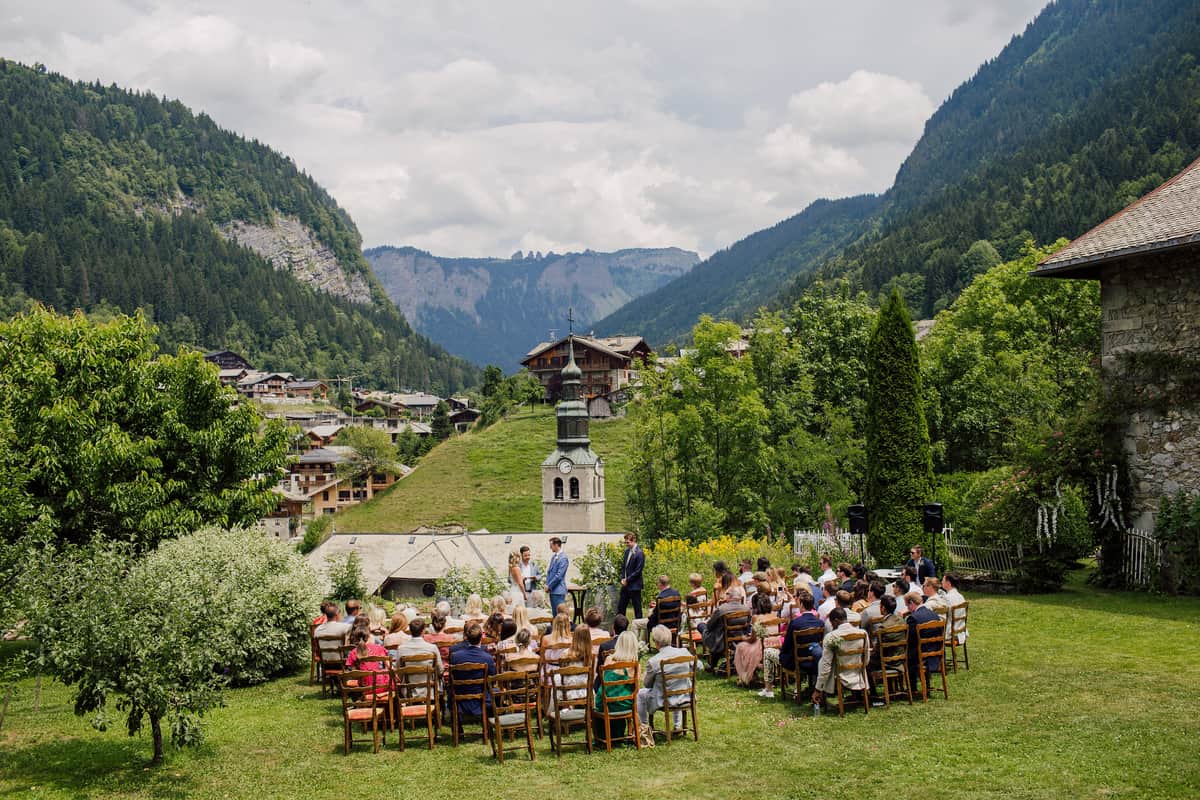 Guests seated in rows for a garden ceremony, with the valley and mountains behind
