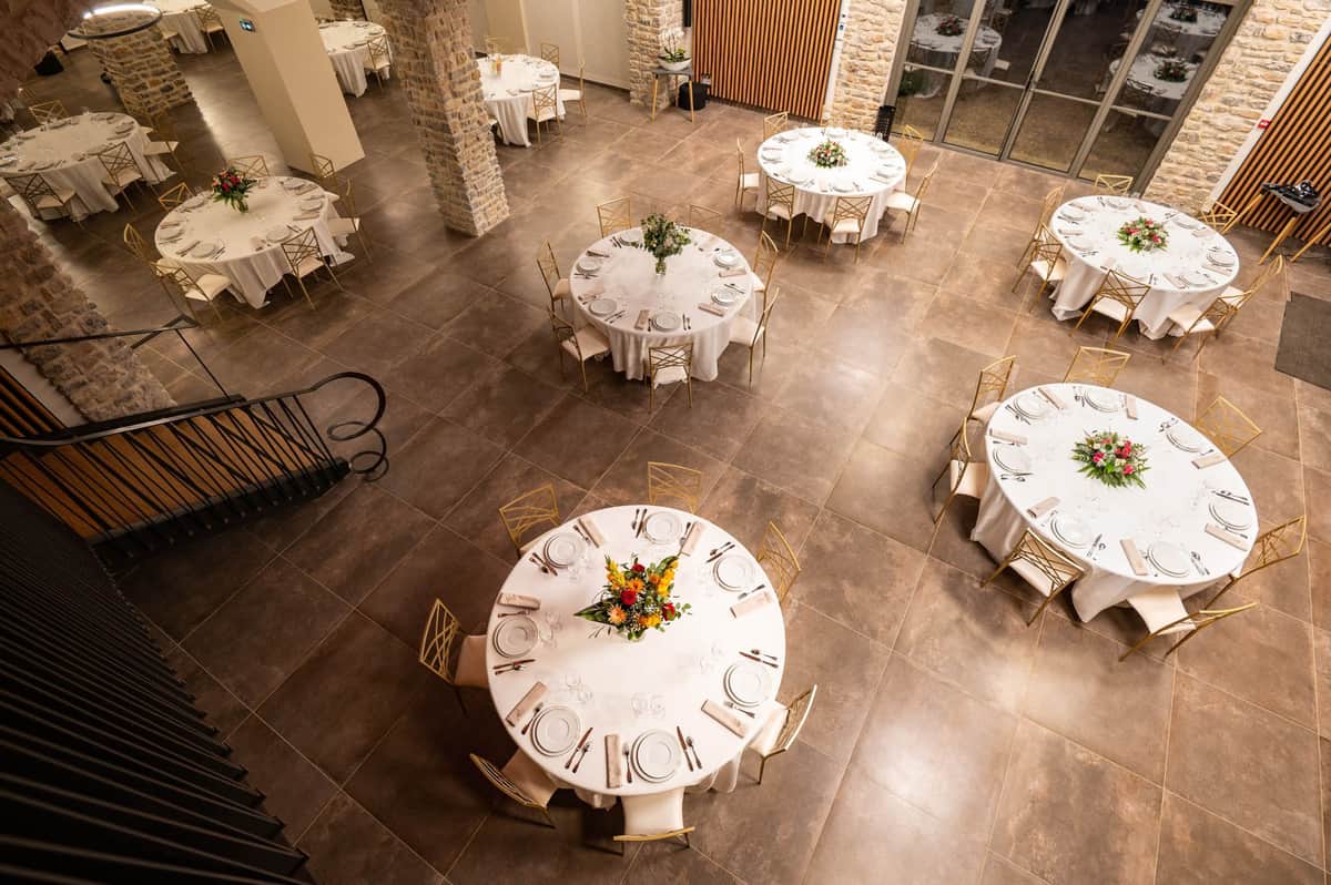 Domaine de Blacailloux bastide reception hall aerial view with round tables gold chairs and floral centerpieces