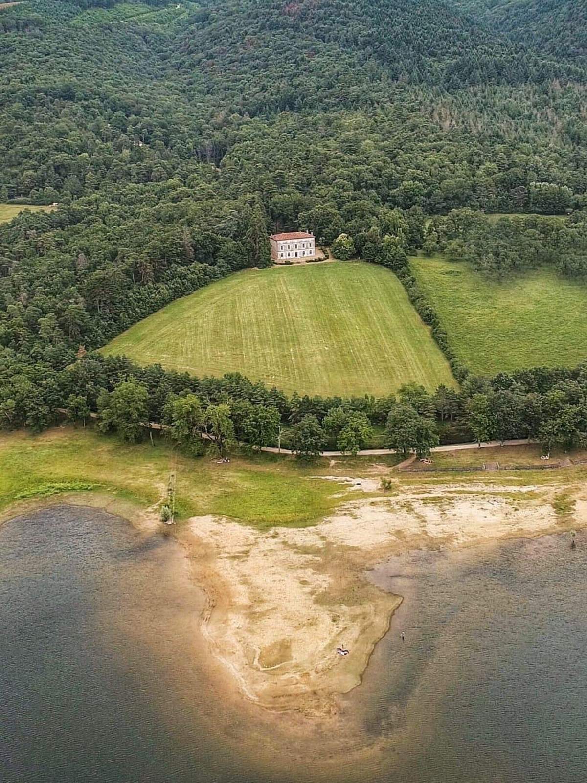 Aerial view of the château set among trees on the shore of Lac de Saint-Ferréol.