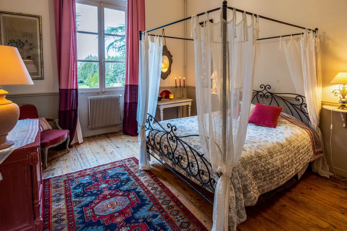 Guest bedroom with a wrought-iron four-poster bed and a patterned rug