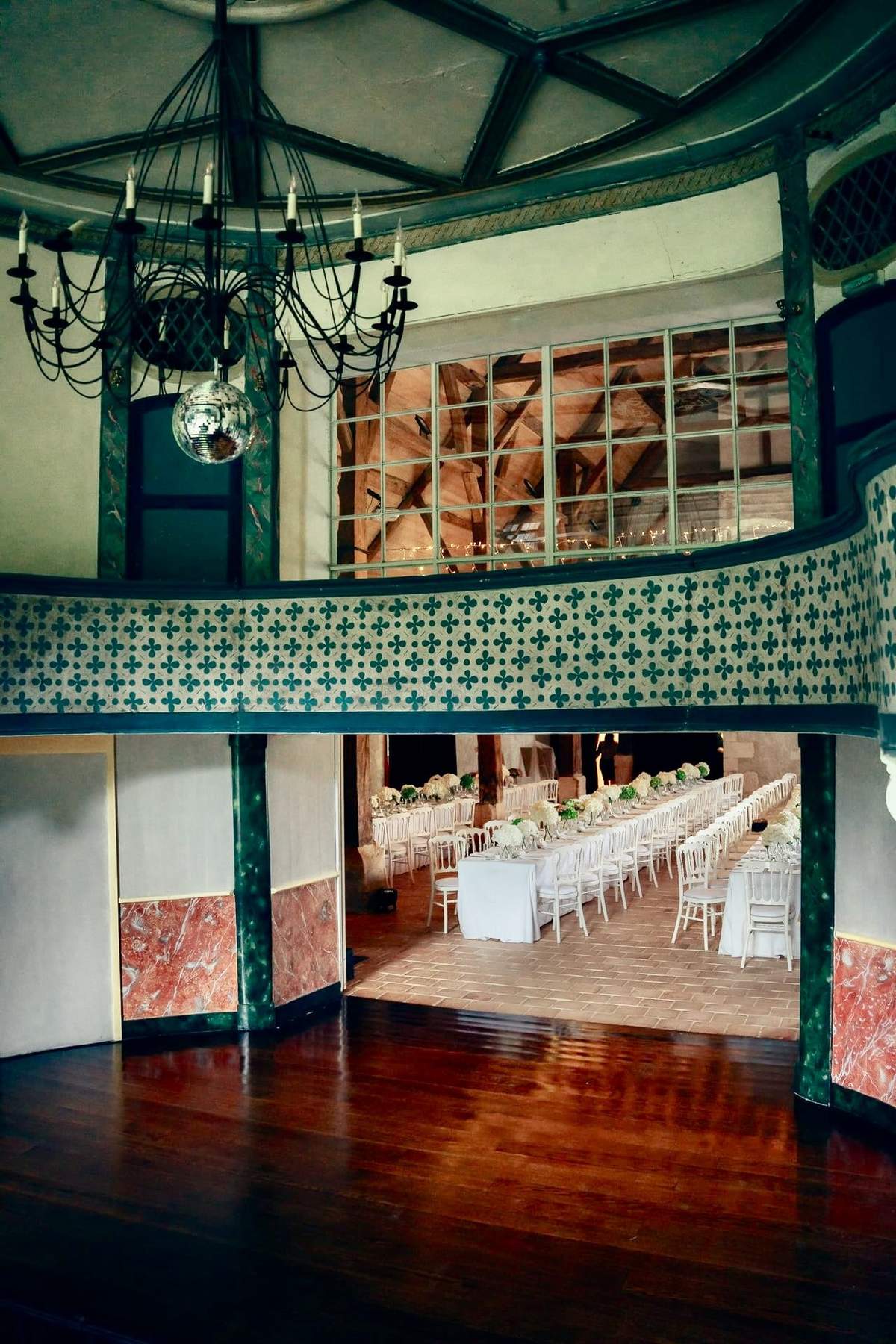 The 18th-century theatre's wooden dance floor, patterned balcony, chandelier and disco ball, opening onto the dinner barn