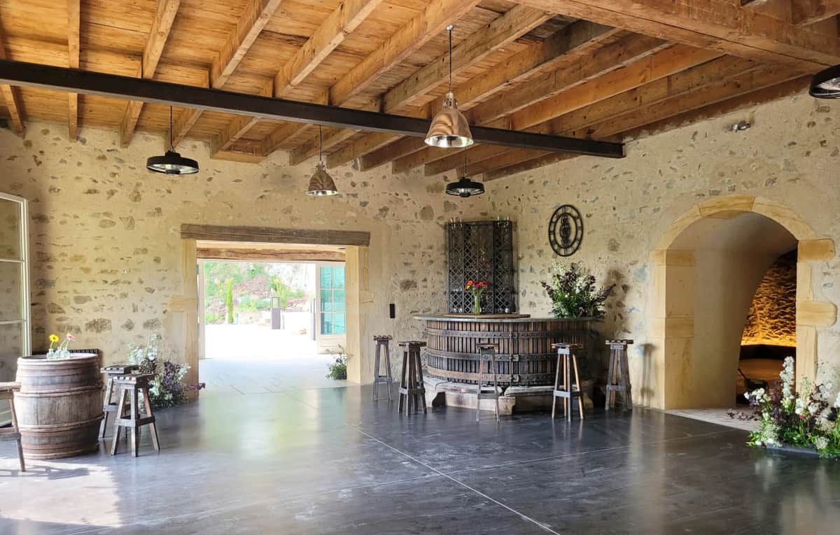 Stone reception barn at Domaine de Vavril with a wine-barrel bar and exposed beams