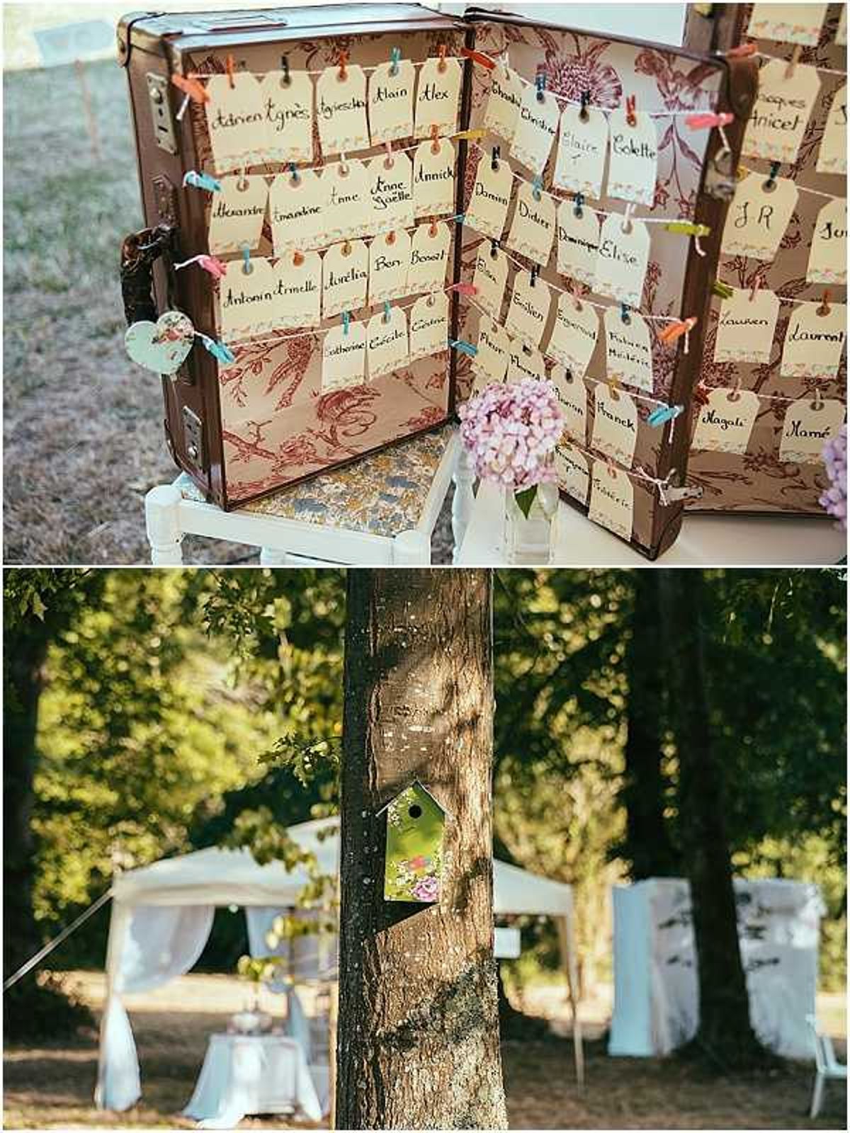 A two-image collage showing outdoor wedding reception details with a vintage travel theme. The top image is a close-up of a seating chart display created inside an open vintage brown suitcase lined with toile-patterned paper; kraft luggage tags handwritten with guest names in French are attached in rows using colorful mini clothespins in orange, blue, green, and red, and a small glass vase with pink hydrangea blooms sits beside the suitcase on a white wooden crate. The bottom image shows a wooded outdoor reception setting with white draped tent structures and white chair covers visible in the background, and a small decorative birdhouse-style sign attached to a tree trunk in the foreground, suggesting a whimsical, rustic styling theme.