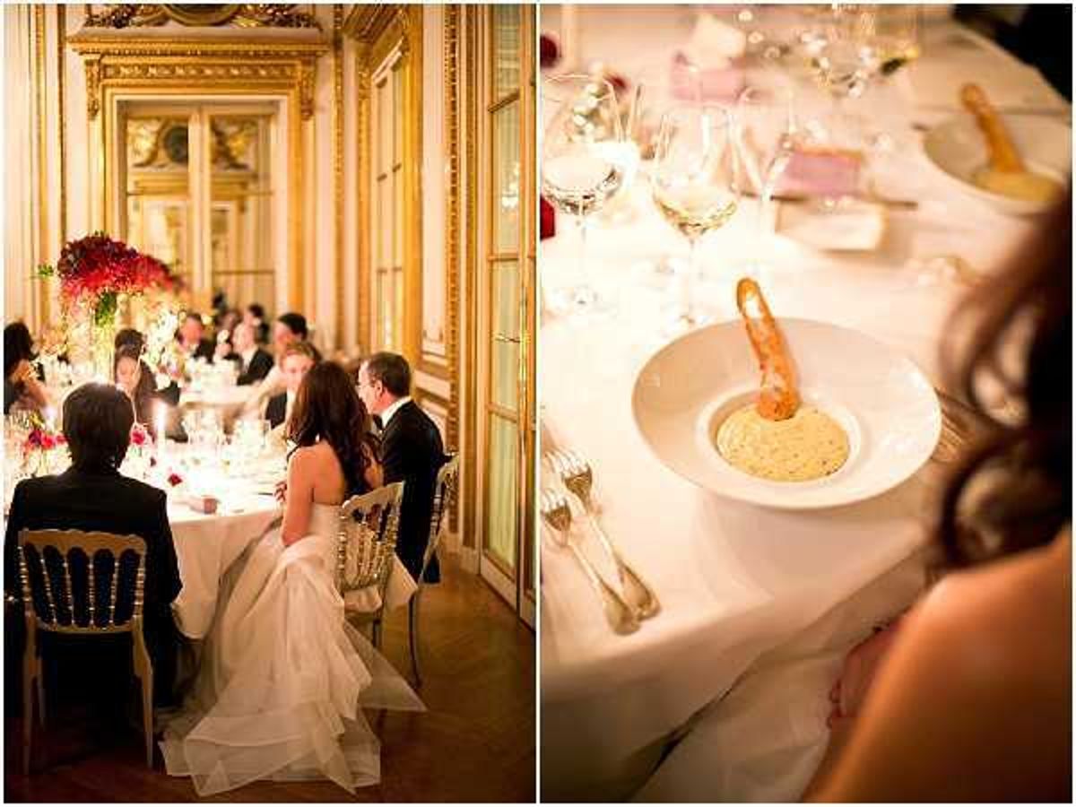A split image showing two scenes from an indoor wedding reception in a formal Parisian-style ballroom with ornate gold-paneled walls and large gilded mirrors. On the left, the bride in a white strapless ball gown sits alongside the groom in a black tuxedo at a long rectangular dining table set with white linens, crystal glassware, and tall centerpieces of deep red floral arrangements; approximately 10-12 guests are visible seated along the table, and gold Chiavari chairs are used throughout. On the right, a close-up detail shot shows a white ceramic soup bowl containing a cream-colored bisque with a whole prawn, placed on a white tablecloth with silver cutlery, crystal wine glasses, and a small pink place card visible in the background. The overall decor palette is gold, white, and deep red, consistent with a classic, formal wedding style.