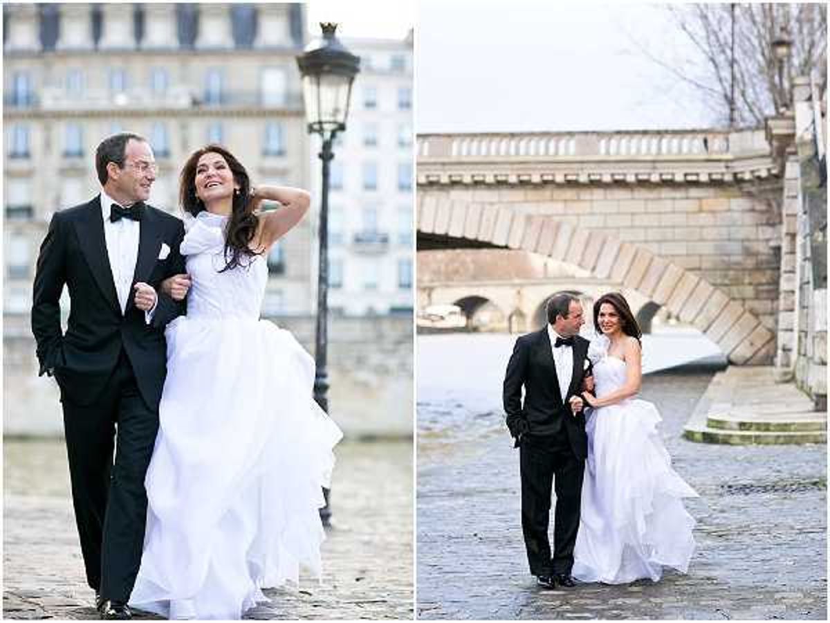 A couple portrait session shown as a side-by-side diptych, taken outdoors along the Seine river in Paris. The groom wears a classic black tuxedo with bow tie and white pocket square, while the bride wears a white ball gown with a ruffled, layered skirt. In the left image, the couple walks arm-in-arm on cobblestones with a Haussmann-style building and a street lamp in the background; in the right image, they walk along the quay with a stone arched bridge over the Seine visible behind them. Both shots are mid-length to full-length portraits with a classic formal styling aesthetic.