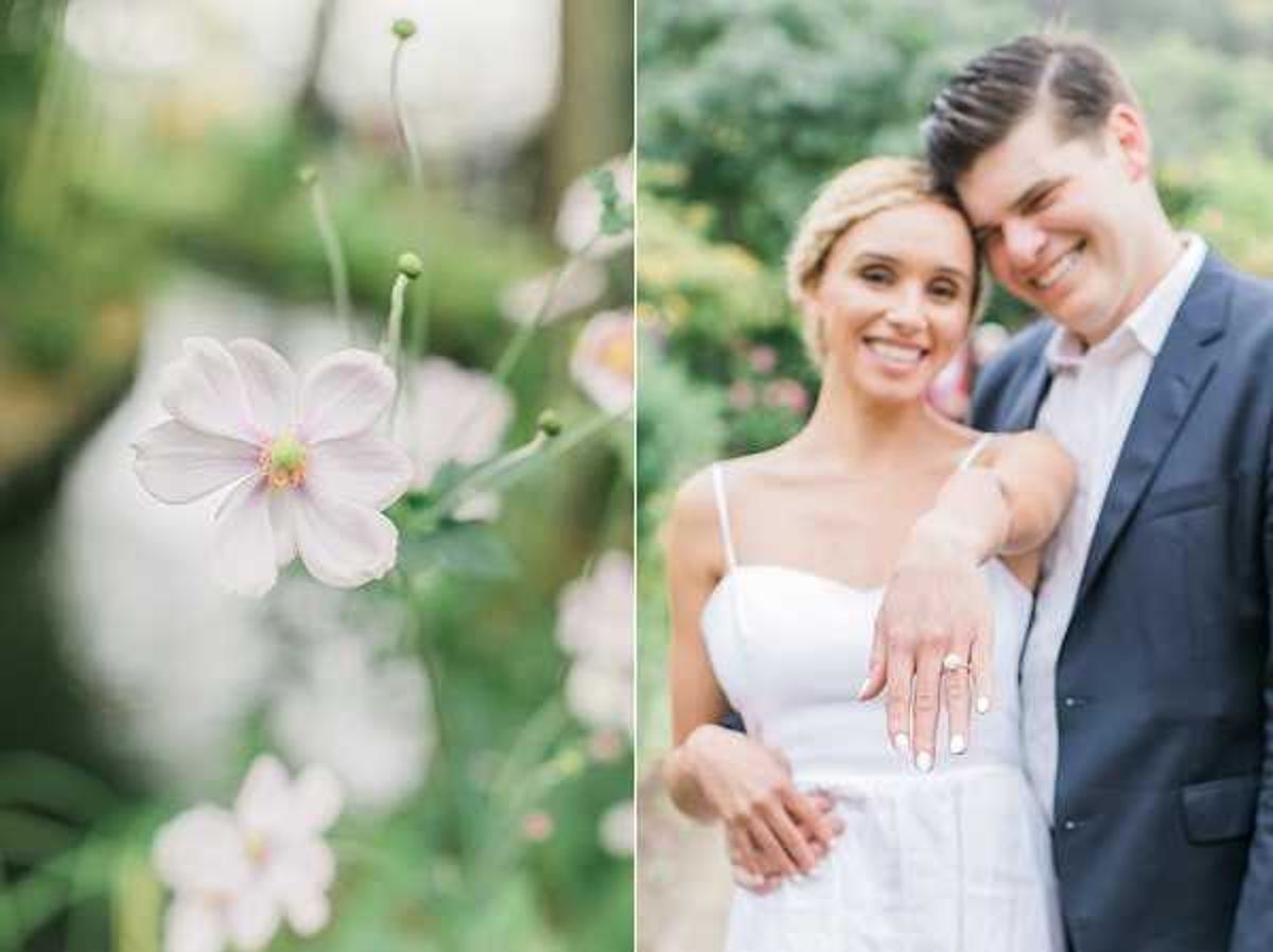 A diptych image combining a close-up detail shot and a couple portrait, likely from an engagement or post-wedding shoot in an outdoor garden setting. The left panel features a shallow depth-of-field close-up of a pale blush pink anemone flower with a soft green bokeh background. The right panel shows a couple posing together outdoors among lush greenery; the woman wears a white spaghetti-strap dress and displays her engagement and wedding rings toward the camera, while the man wears a navy blue suit jacket with a light pink shirt. Both are smiling broadly with their cheeks touching in a relaxed, candid-style portrait composition.