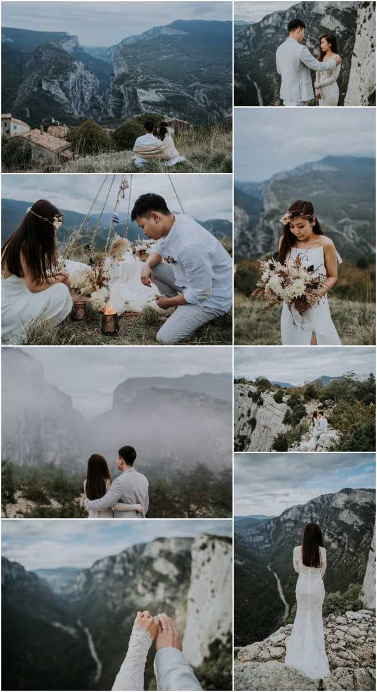 A collection of eight outdoor elopement or couple session photographs taken at a dramatic canyon overlook, likely the Gorges du Verdon in southern France. The couple consists of a woman wearing a white lace or embroidered fitted gown with long sleeves or a sleeveless style depending on the shot, a floral hair accessory, and carrying a bouquet of cream and ivory dried and fresh flowers including pampas grass, dried palms, white dahlias, and dark accents; the man wears an all-white linen shirt and light grey trousers. Across the images, the couple is shown sitting at a cliff edge overlooking the valley, kneeling beside a boho-style picnic setup with a macramé or rope hanging decoration, dried floral arrangements, candle lanterns, and a small white cake set in dry grass; posing together in portrait shots against rocky cliff faces; holding hands in a close-up detail shot showing lace sleeve detail and a ring; and a rear-view portrait of the bride standing alone on a rocky ledge overlooking the canyon. The styling is distinctly bohemian with natural, earthy tones — dried botanicals, warm neutrals, candlelight, and a relaxed, intimate atmosphere. Shots include wide landscape portraits, medium couple portraits, close-up detail, and a rear-view composition.