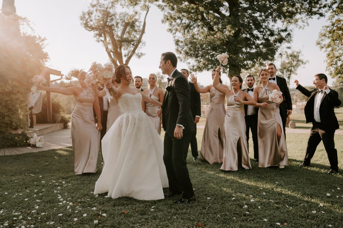 Bridal party celebrating at golden hour with champagne-gold bridesmaids and tuxedoed groomsmen