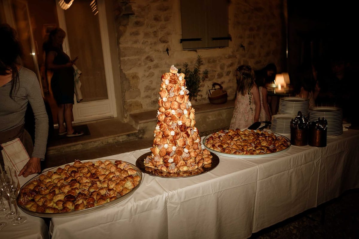 Tall croquembouche profiterole tower with spun sugar on white dessert table at evening reception