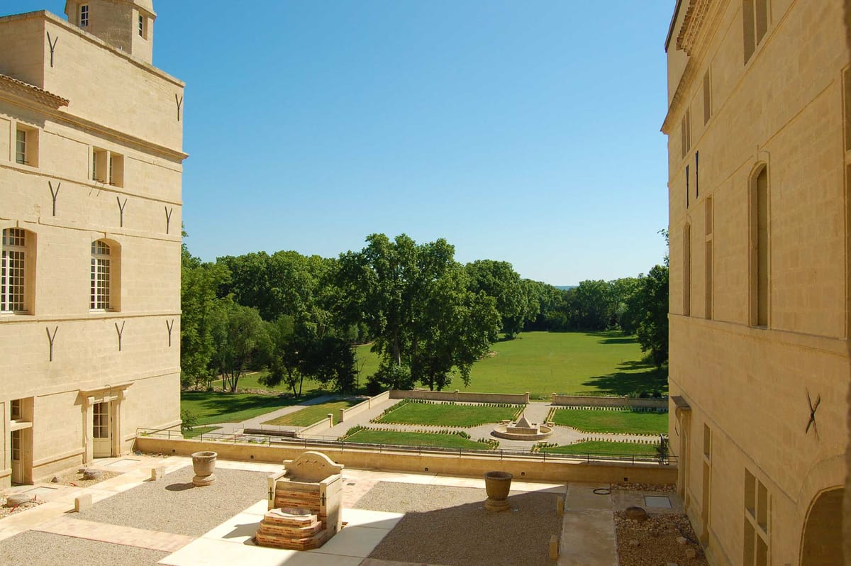 Elevated view from chateau terrace over parterre garden with fountain leading to open lawn and mature trees