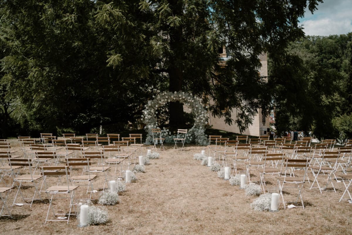 Ceremony setup with baby breath circular arch white folding chairs and pillar candle aisle markers