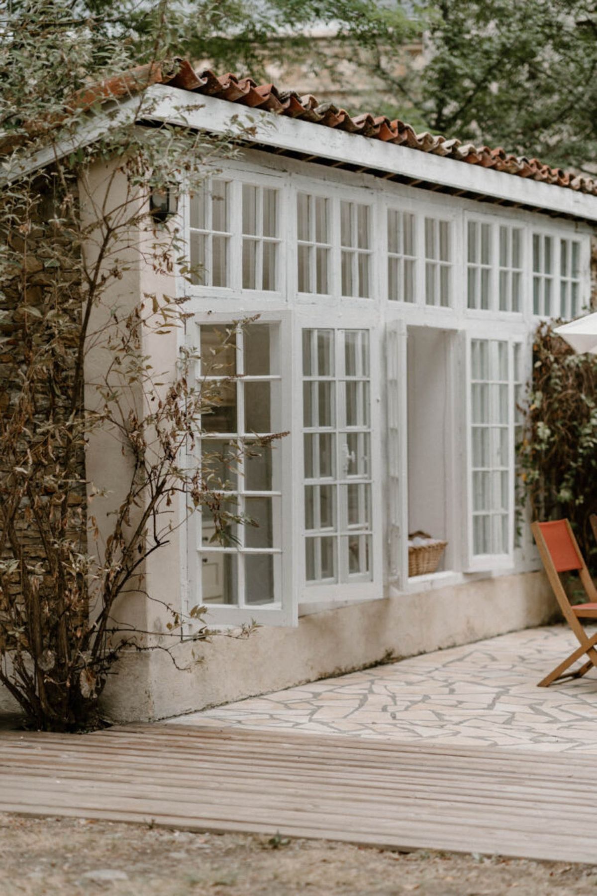 White-framed orangery with terracotta roof and wooden decking at French country property