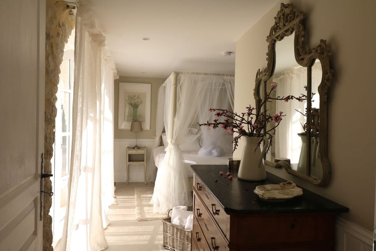 Bridal suite with four-poster canopy bed, gilt baroque mirror, cherry blossom pitcher, and stone surrounds