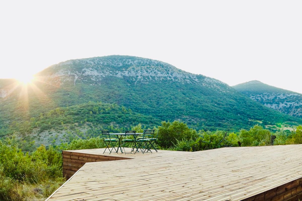 Wooden deck terrace with green bistro chairs facing panoramic valley landscape