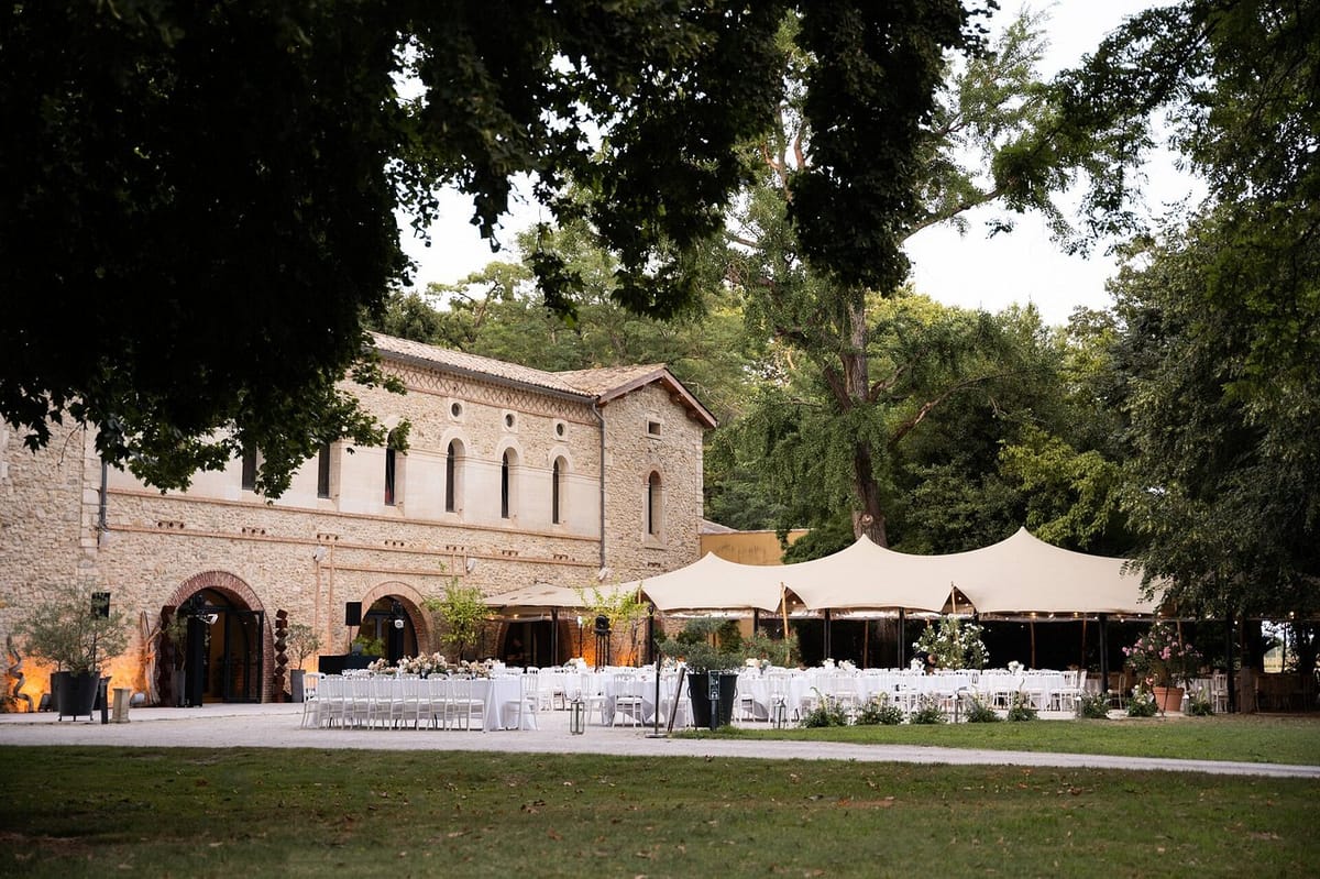 Dusk reception with round tables under stretch tents fairy lights white and blush centerpieces before stone abbey facade
