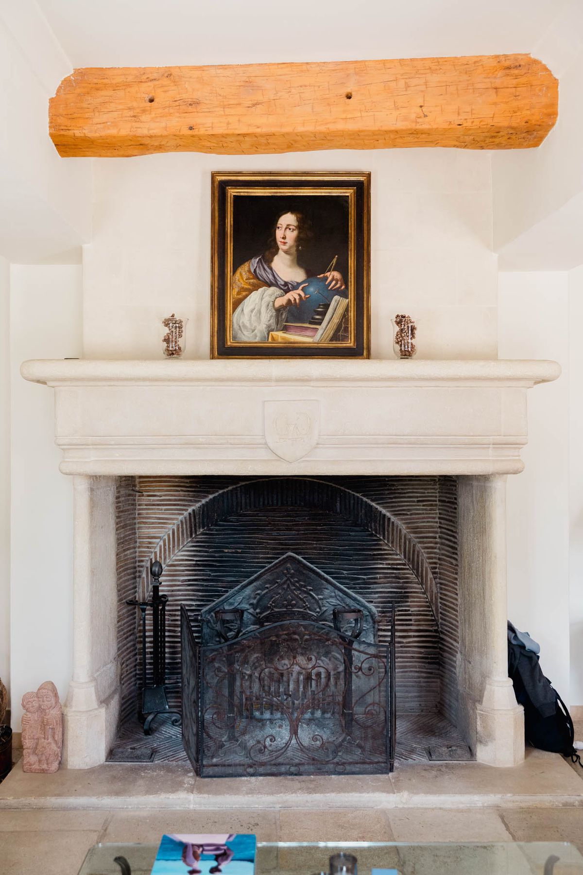 Carved stone fireplace with heraldic shield wrought iron screen and Old Master painting in chateau interior