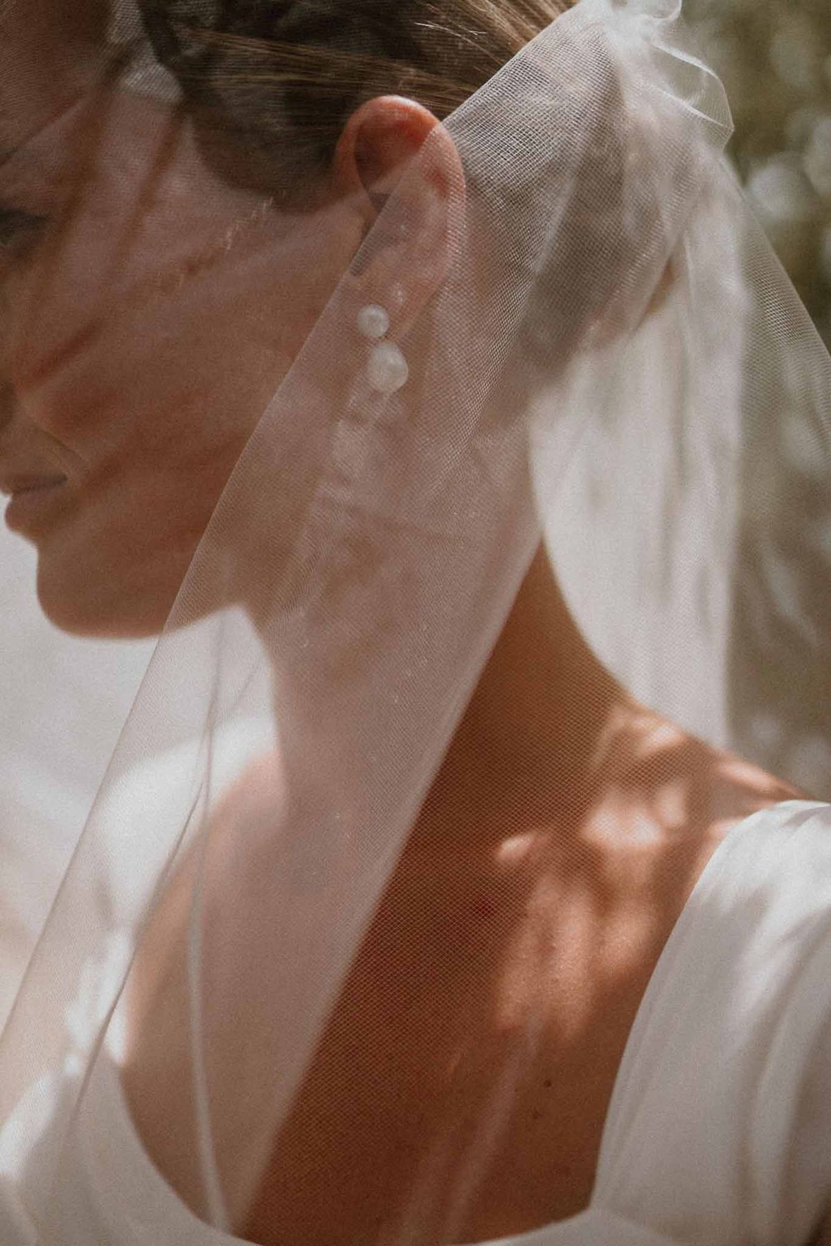 Bride's pearl earrings and veil in dappled light at Château Sainte-Roseline