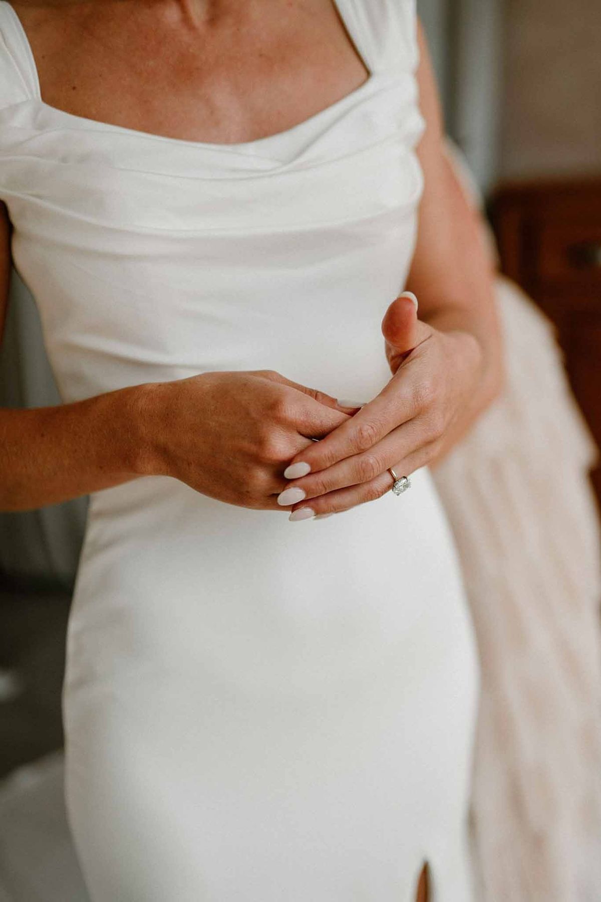 Bride's hands with engagement ring against satin gown at Château Sainte-Roseline