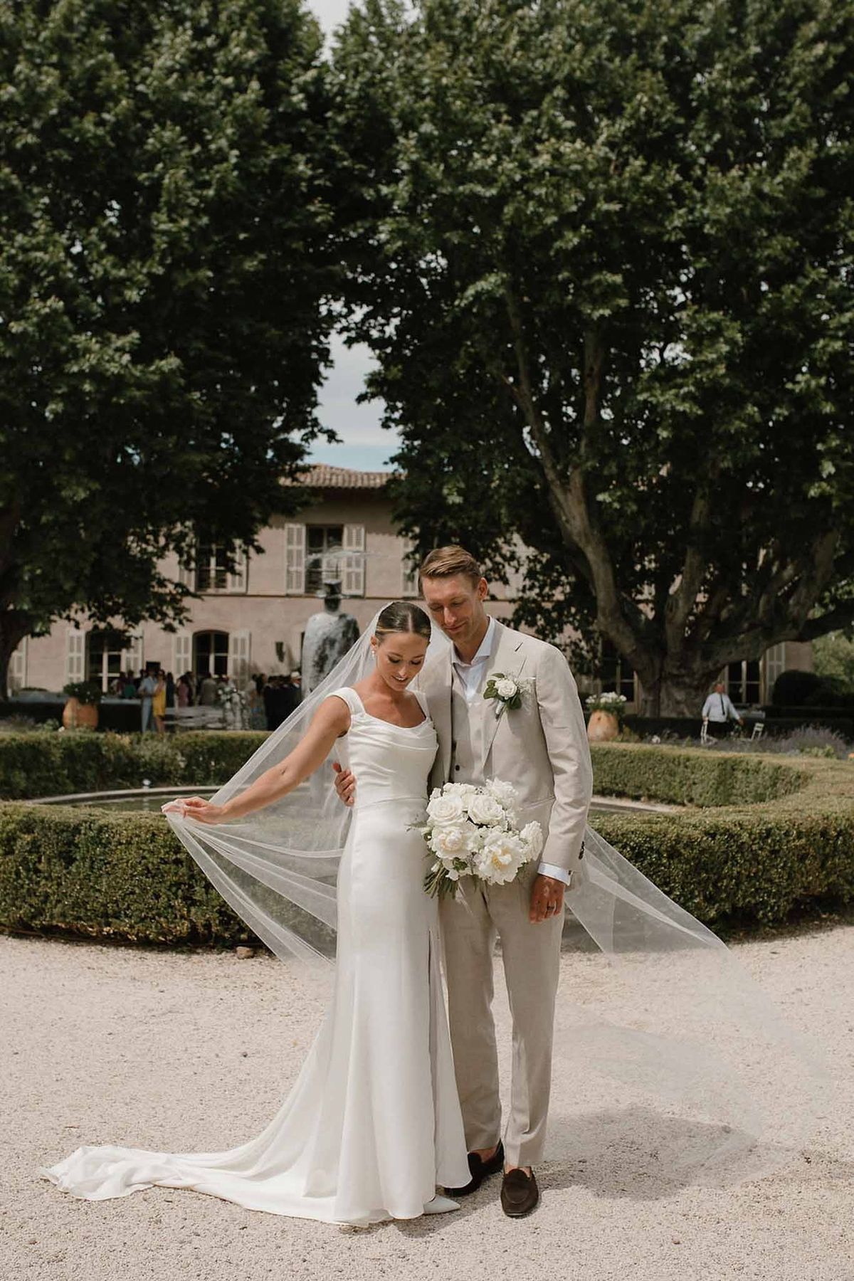 Couple walking in formal garden with château façade at Château Sainte-Roseline