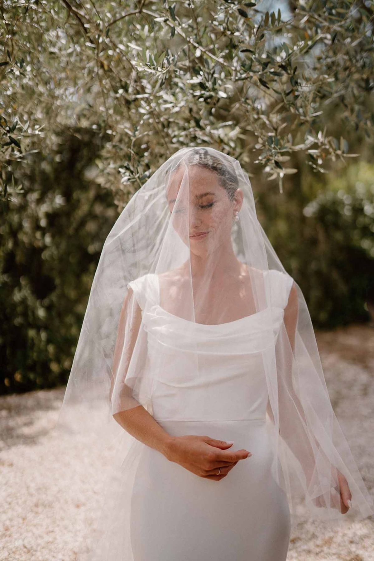 Bride looking down under veil with olive branches at Château Sainte-Roseline