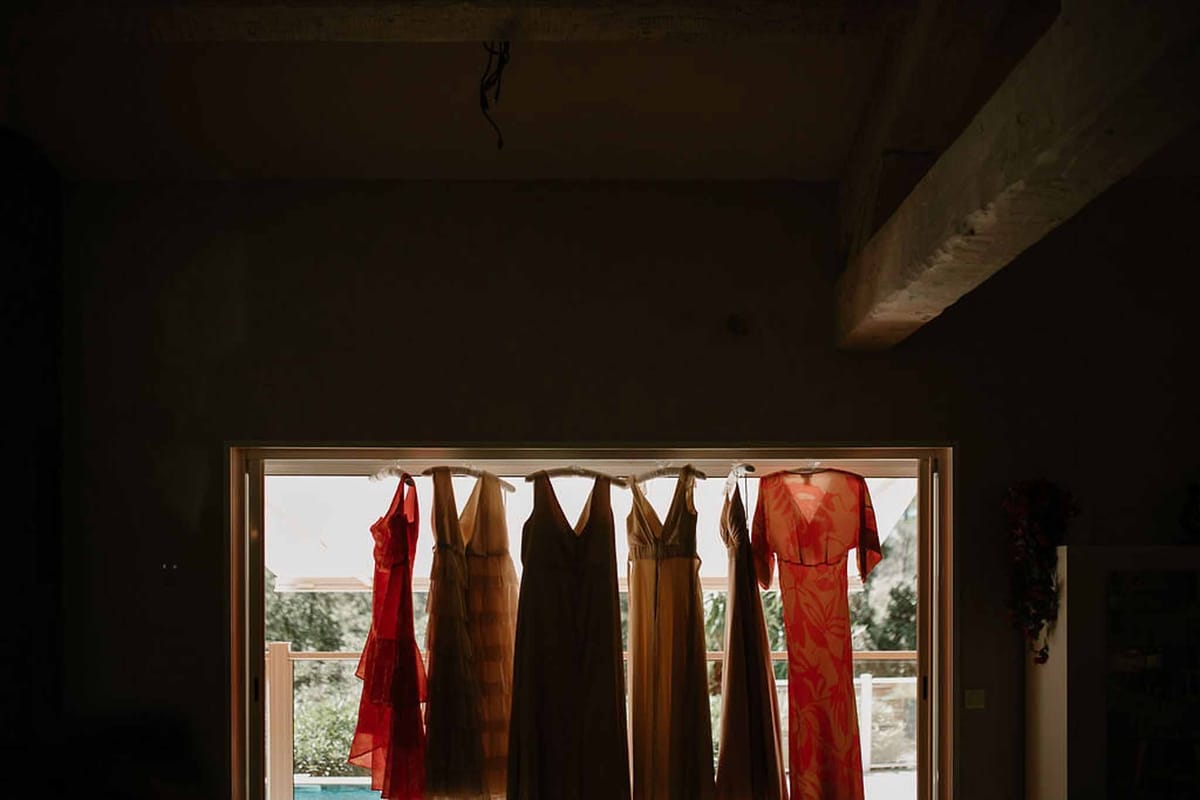 Mismatched bridesmaid dresses hanging in window at Château Sainte-Roseline