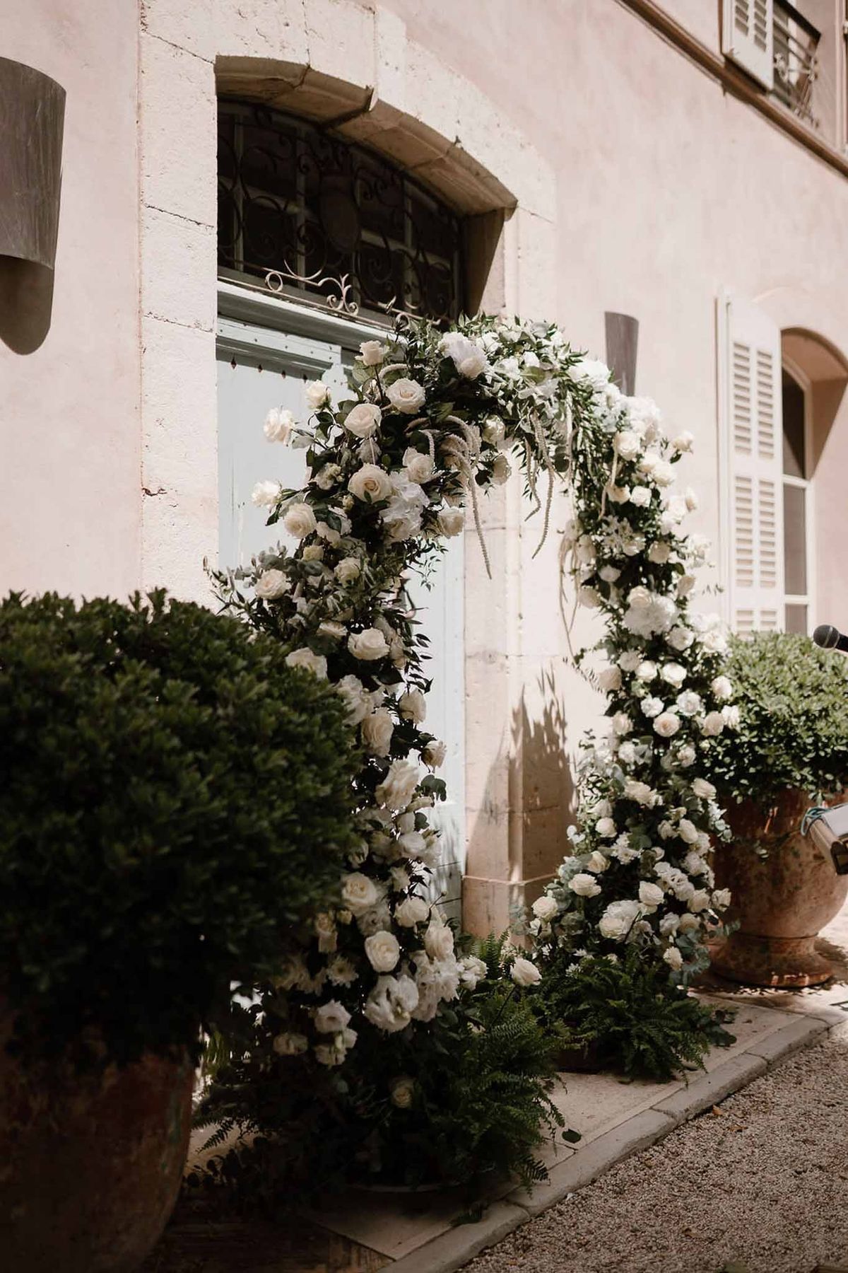 Close-up of white rose ceremony arch with olive branches at Château Sainte-Roseline