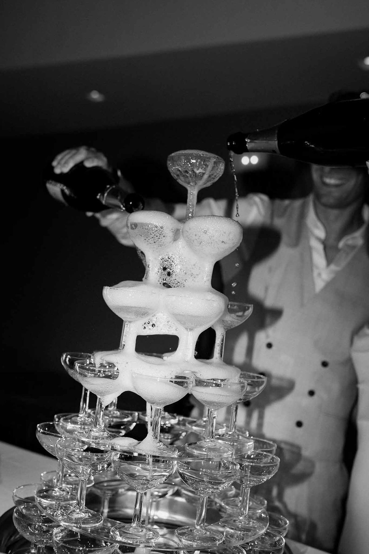 Couple pouring champagne tower in black and white at Château Sainte-Roseline