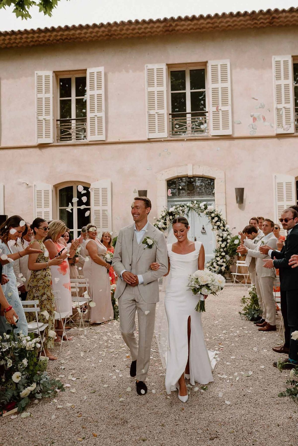 Couple walking through petal toss in courtyard at Château Sainte-Roseline
