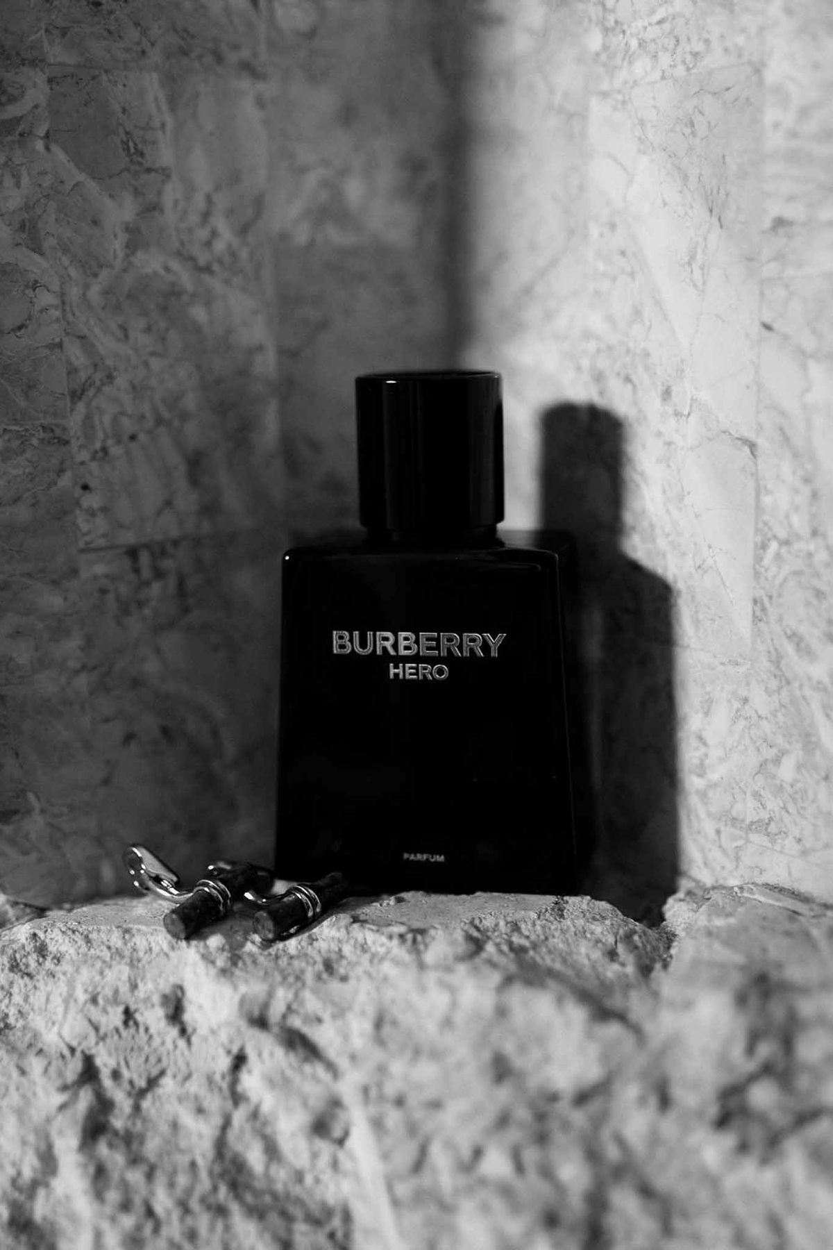 Burberry Hero perfume and cufflinks on stone wall in black and white at Château Sainte-Roseline