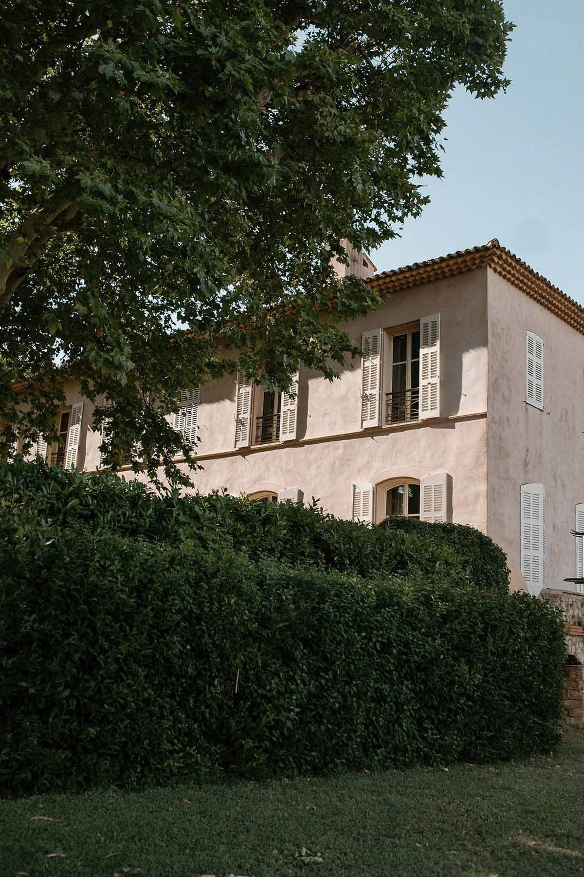 Pink façade of Château Sainte-Roseline with plane tree and hedges