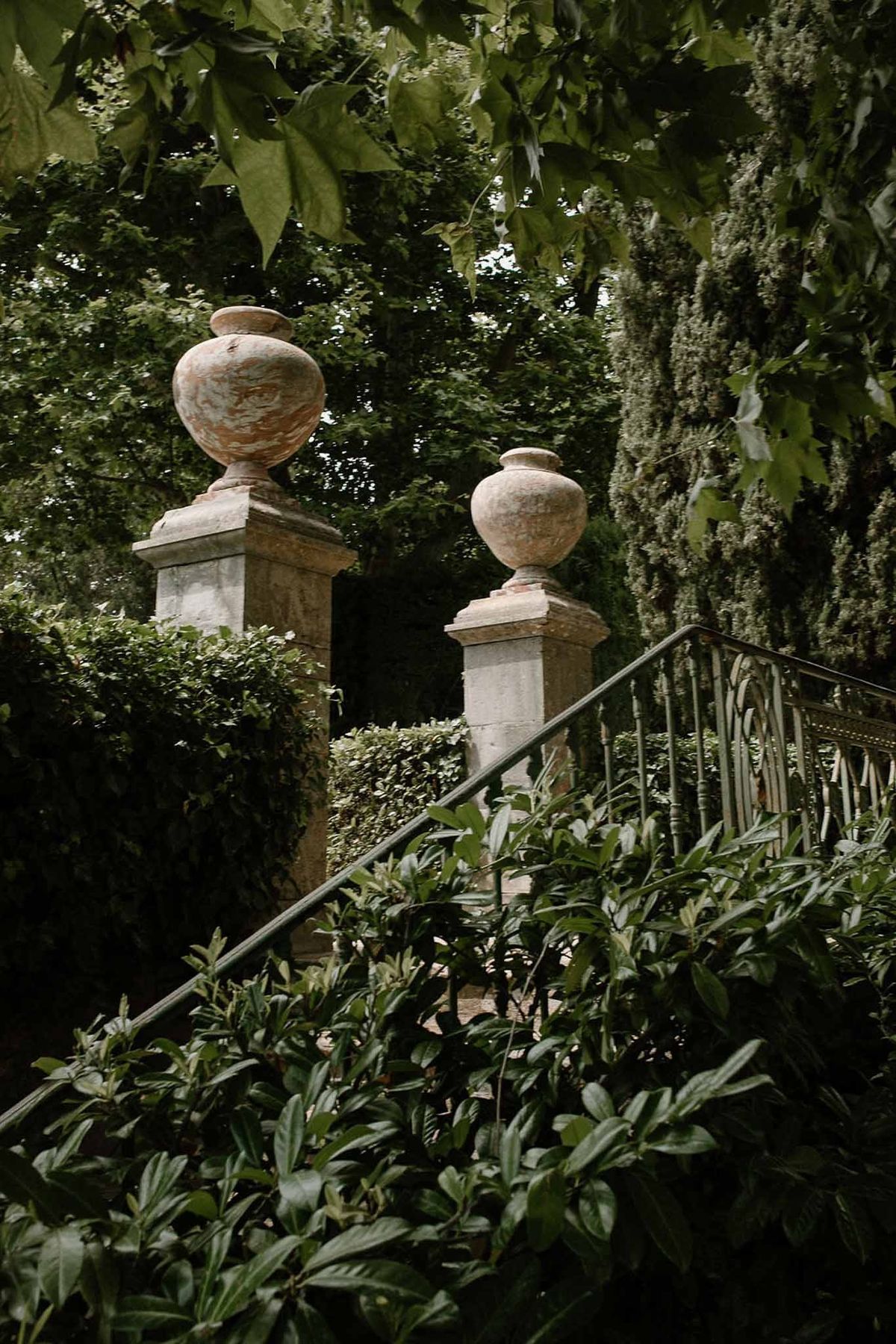 Stone urns on pillars at garden entrance with hedges at Château Sainte-Roseline
