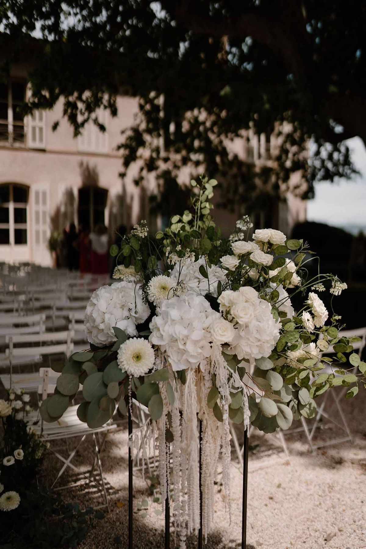 White floral ceremony arrangement with château behind at Château Sainte-Roseline