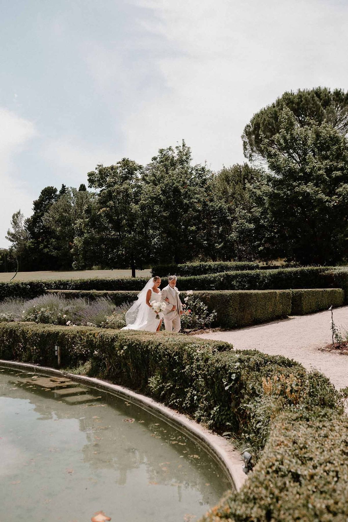 Father walking bride past garden fountain at Château Sainte-Roseline
