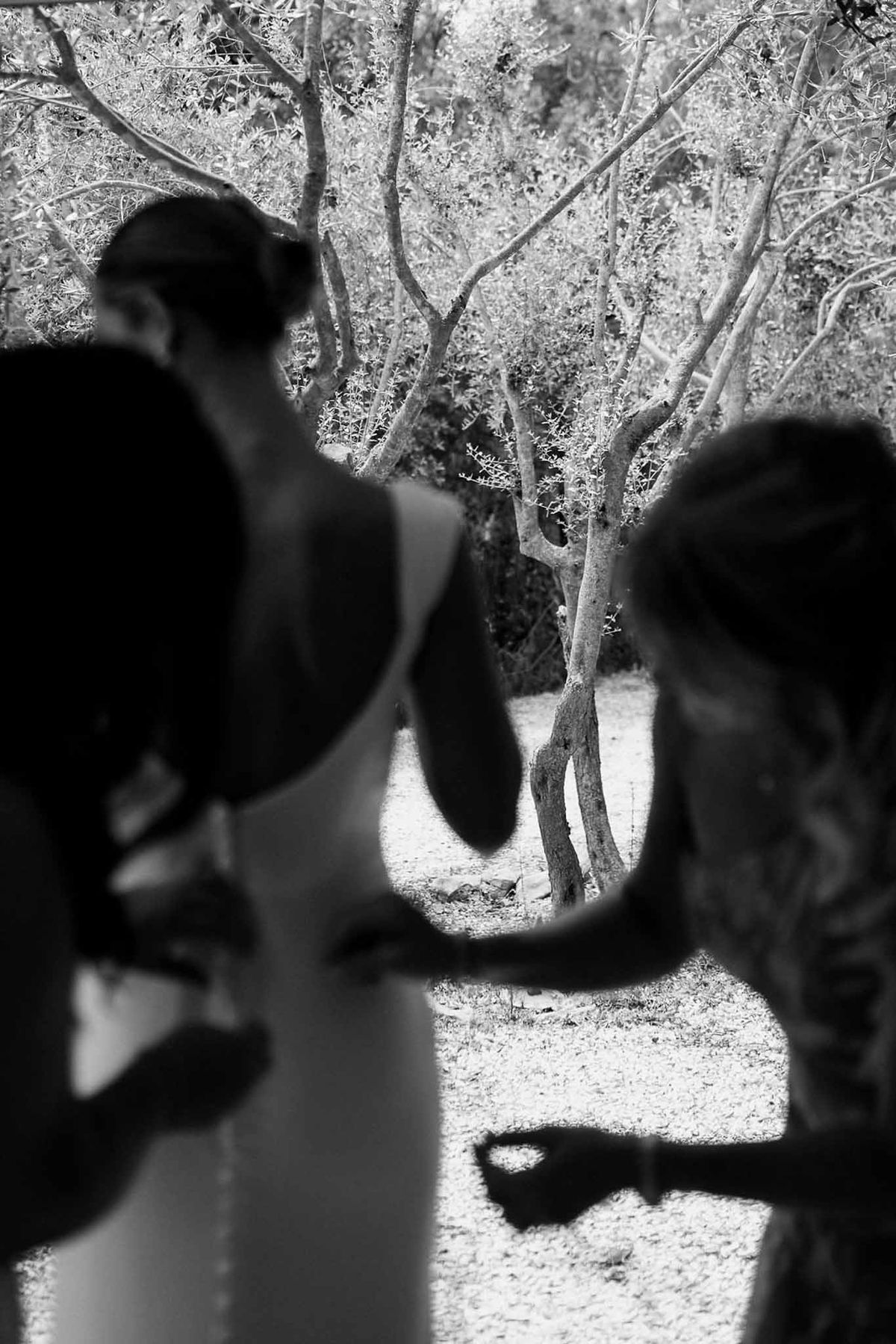 Bride's back silhouette with olive grove through doorway in black and white at Château Sainte-Roseline