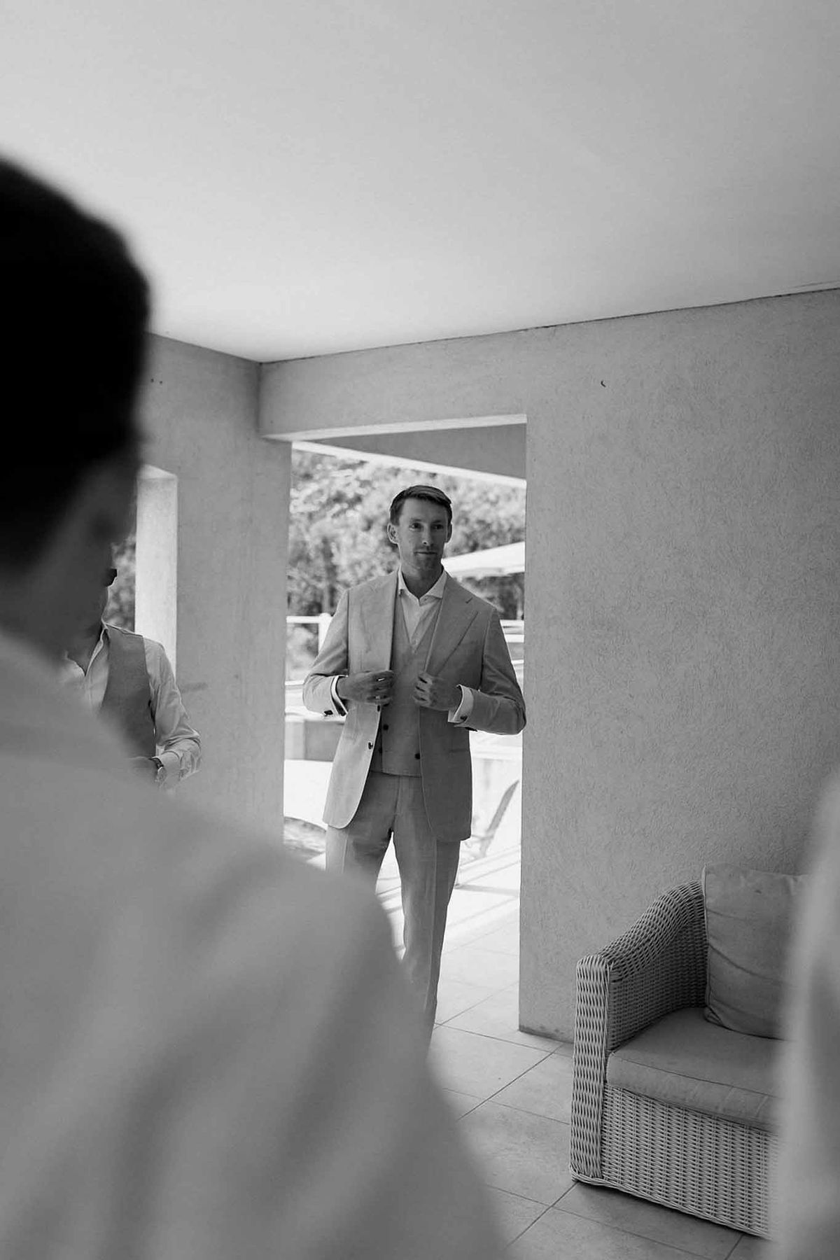 Groom checking suit in mirror on terrace in black and white at Château Sainte-Roseline