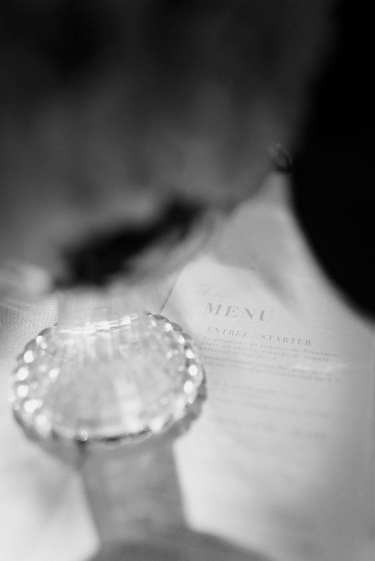 Letterpress menu card behind cut crystal salt cellar in soft black and white close up at Château Sainte-Roseline
