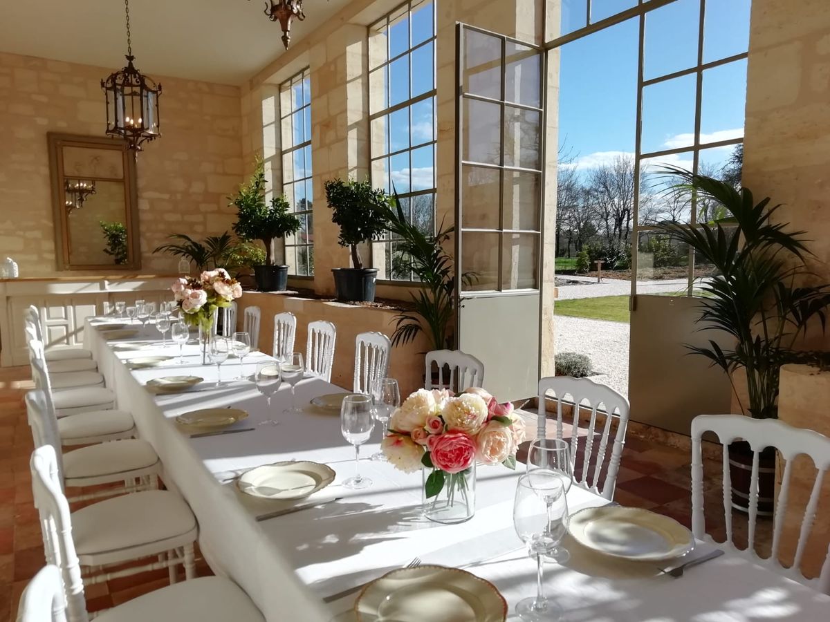 Orangery reception table with blush and coral roses, gold charger plates, and topiary plants