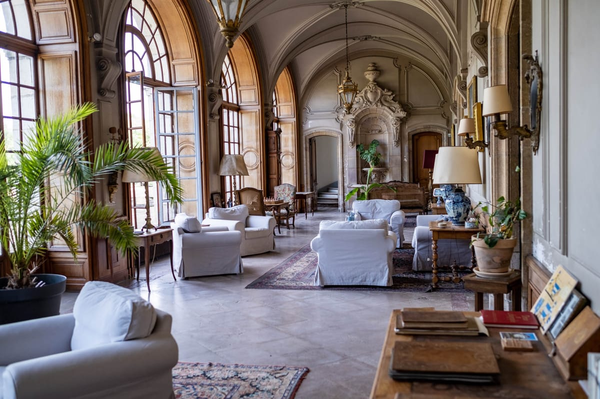 Grand chateau salon with vaulted plasterwork ceiling slipcovered sofas Persian rugs and potted palms