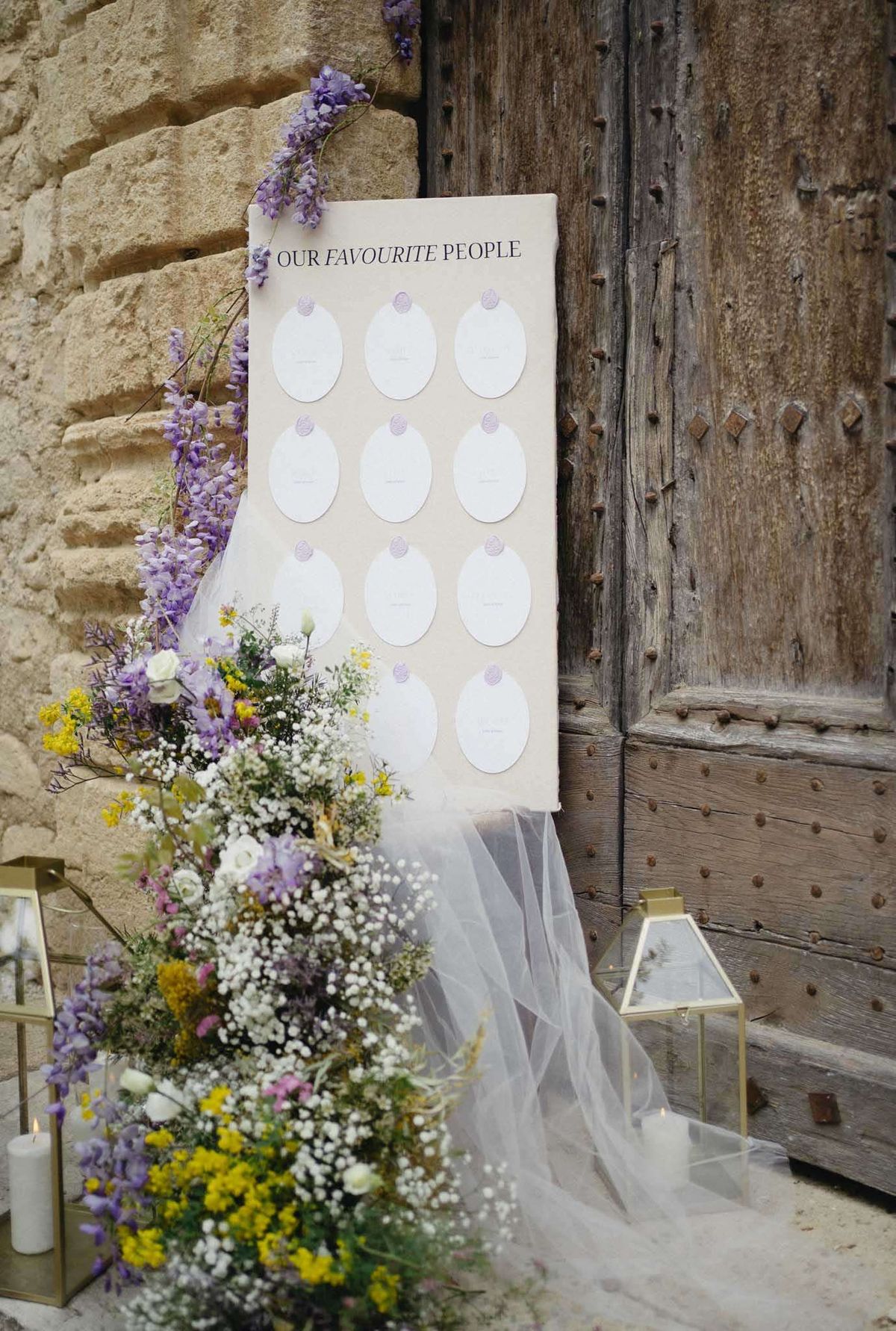 Seating chart with lavender wax seals and wildflower arrangement of mimosa and wisteria at base