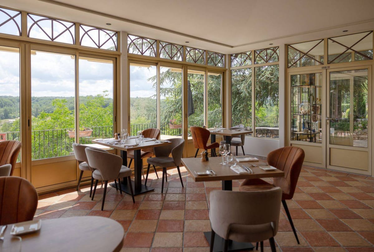 Conservatory dining room with arched windows, terracotta checkerboard floor, and velvet and leather chairs