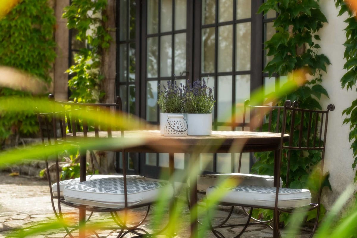 French venue terrace with bistro table, wrought-iron chairs, potted lavender, and steel-framed glass doors