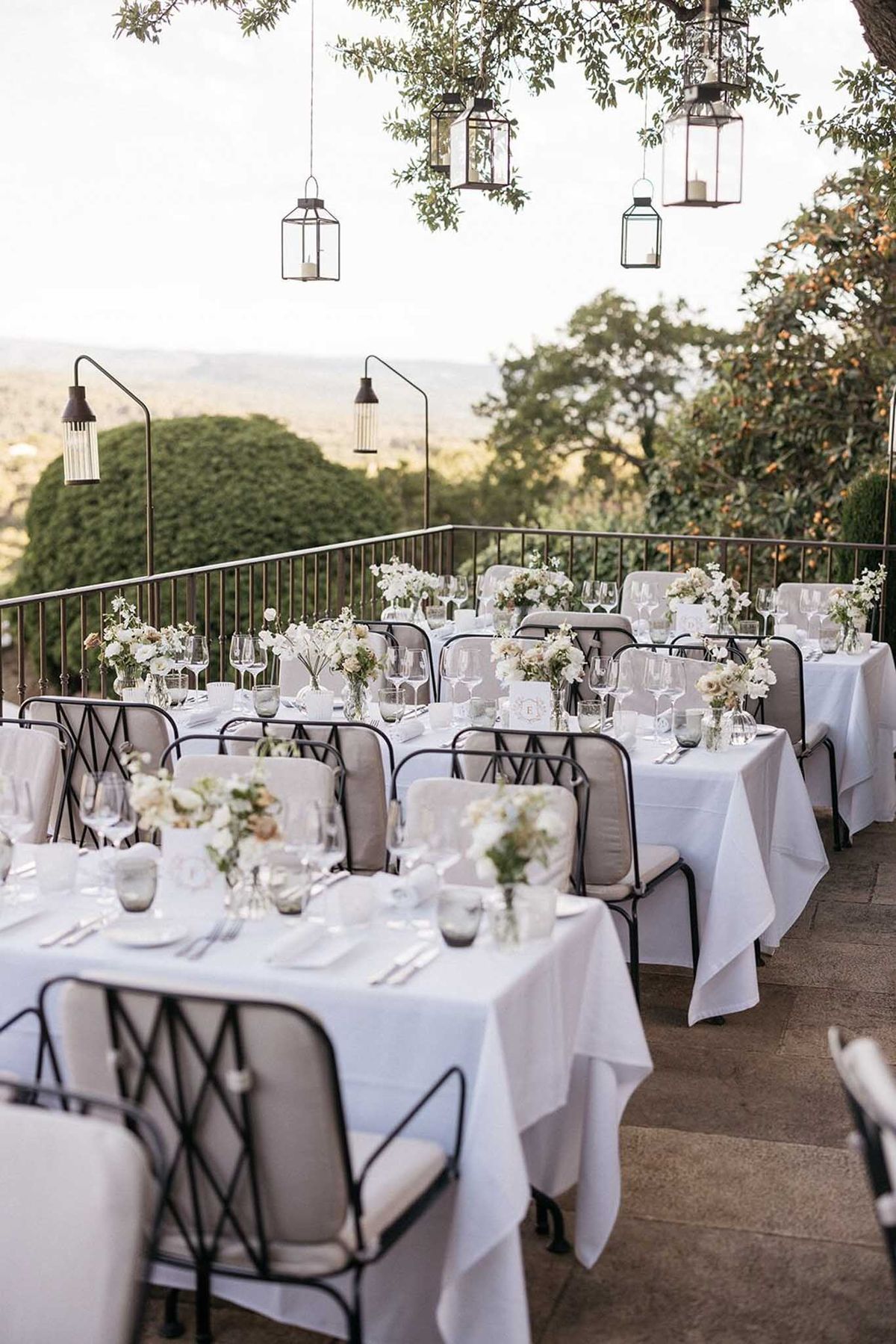 Terrace reception with hanging lanterns white and blush flowers smoked glass votives and valley views