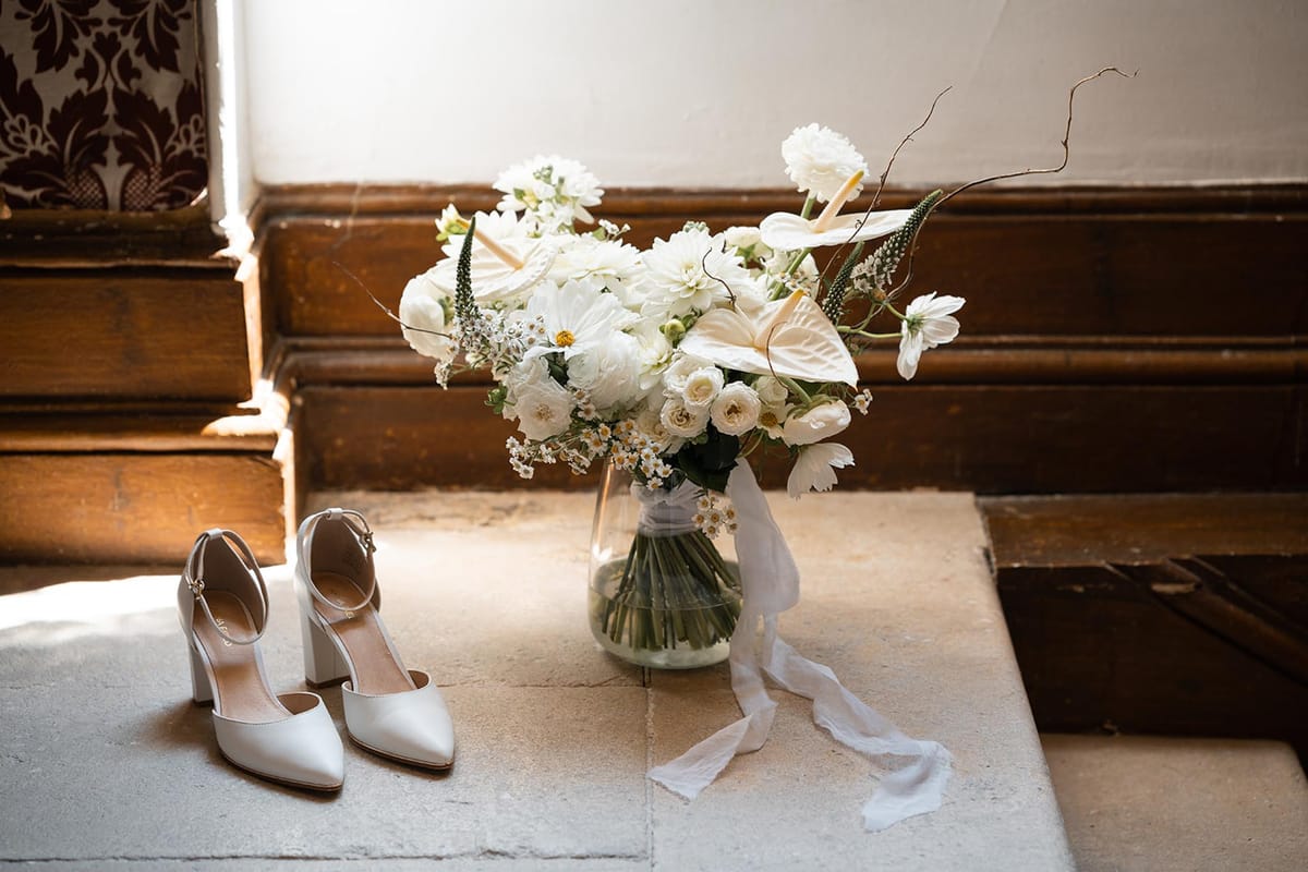 Bridal shoes and bouquet arranged on a stone floor at a French chateau
