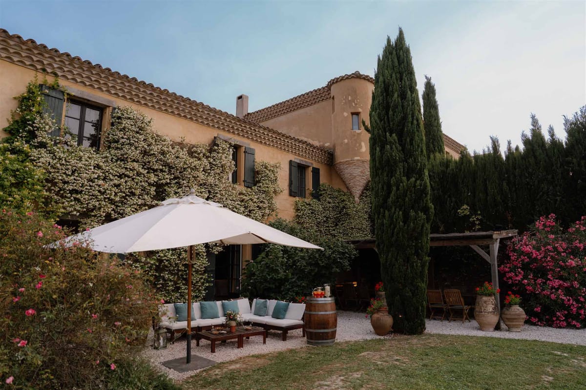 Ochre Provencal mas courtyard with white sectional lounge, wine barrel bar, and climbing vine facade